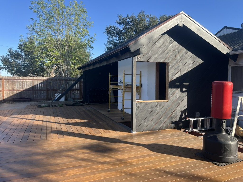 Moody dojo exterior with blackened cedar siding, pond under construction, and installed glass door