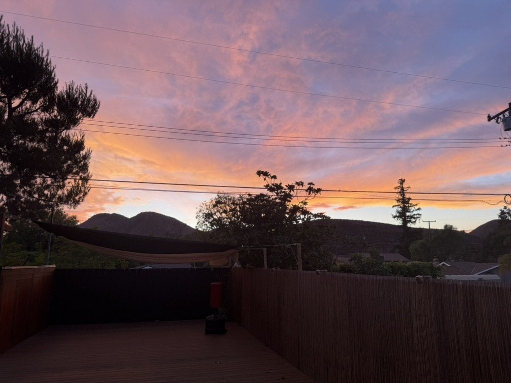 Sunset sky over dojo with bamboo fence and mountain backdrop